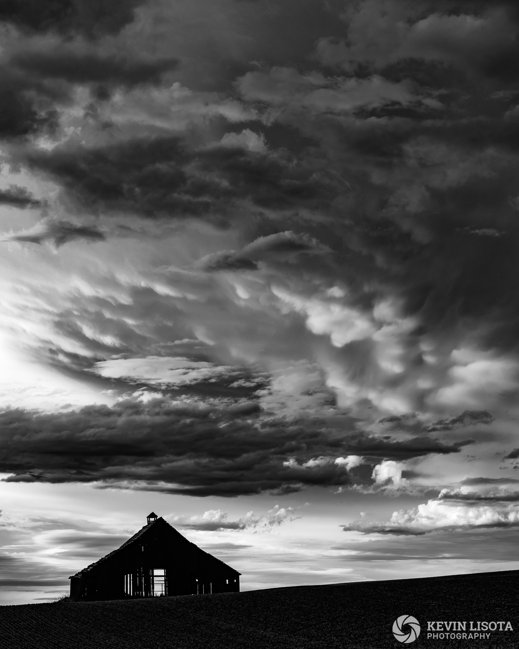 Thunderstorm clouds over old barn at Ladow Butte